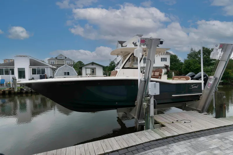 Slide: The Image of 2023 Scout 277 LXF boat on lift by waterfront homes. - 2