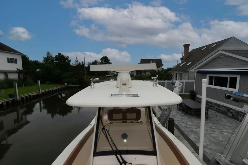 Slide: The Image of 2023 Scout 277 LXF boat docked near waterfront homes under a cloudy sky. - 20