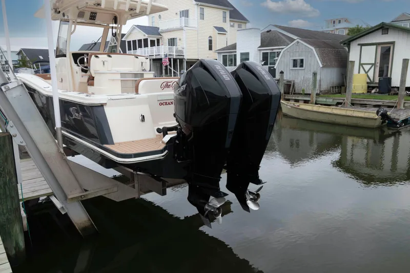 Slide: The Image of 2023 Scout 277 LXF boat with dual outboard motors docked in a marina. - 22