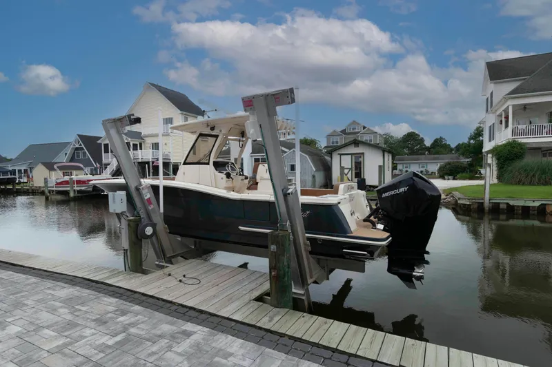 Slide: The Image of 2023 Scout 277 LXF boat docked in a scenic waterfront neighborhood. - 3