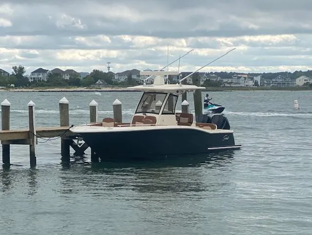 Slide: The Image of 2023 Scout 277 LXF boat docked by a pier on a cloudy day. - 4