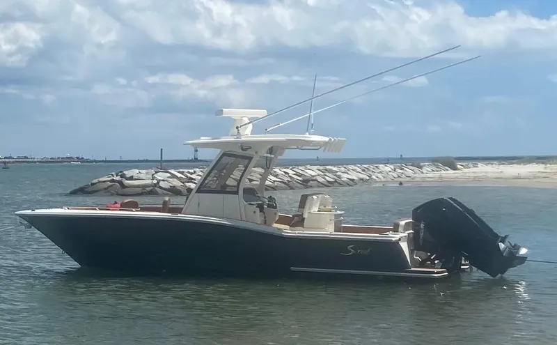 Slide: The Image of 2023 Scout 277 LXF boat on calm water near rocky shoreline under cloudy sky. - 5