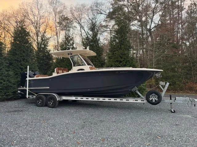 Slide: The Image of 2023 Scout 277 LXF boat on trailer, parked outdoors near trees. - 6