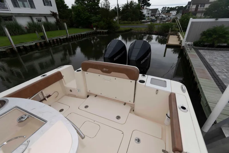 Slide: The Image of 2023 Scout 277 LXF boat with dual Mercury engines docked by waterfront homes. - 9