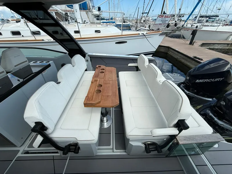 Slide: The Image of 2024 Saxdor 320 GTO boat interior with white seating and wooden table, docked at marina. - 7