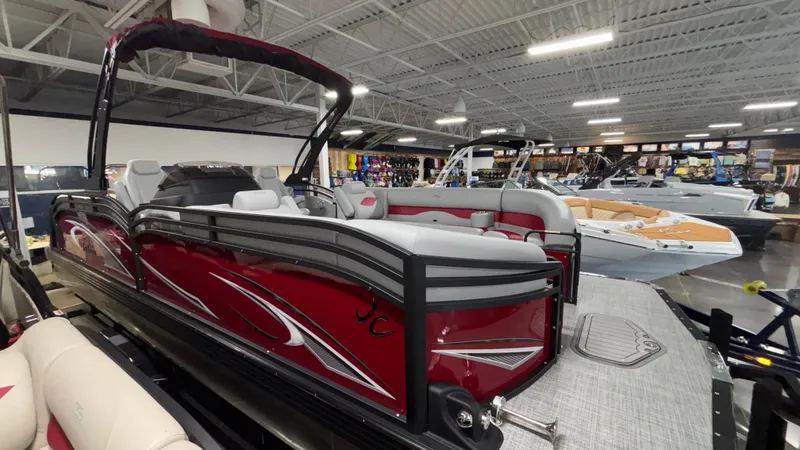 Slide: The Image of 2025 JC Neptoon 25TT Sport pontoon boat displayed in a showroom with other boats. - 30