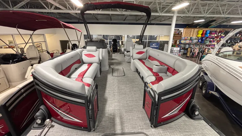 Slide: The Image of 2025 JC Neptoon 25TT Sport pontoon boat with red and gray seating in showroom. - 5