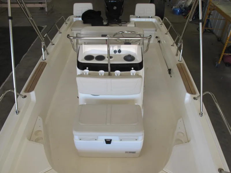 Slide: The Image of 2018 Boston Whaler 170 Montauk interior with seating and console, in a garage setting. - 4