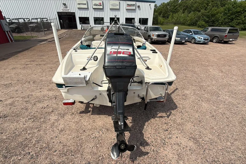 Slide: The Image of 1999 Bayliner 1800 Capri boat with outboard motor in a dealership lot. - 2