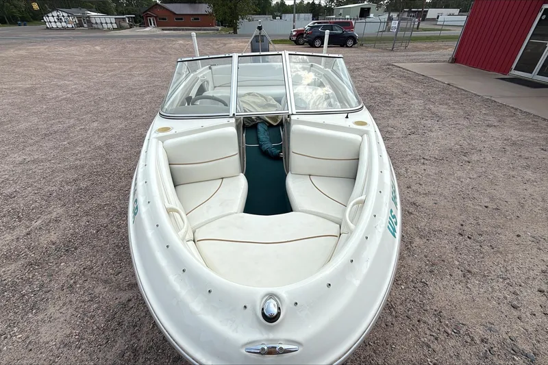 Slide: The Image of 1999 Bayliner 1800 Capri boat with white seating, parked on gravel. - 5