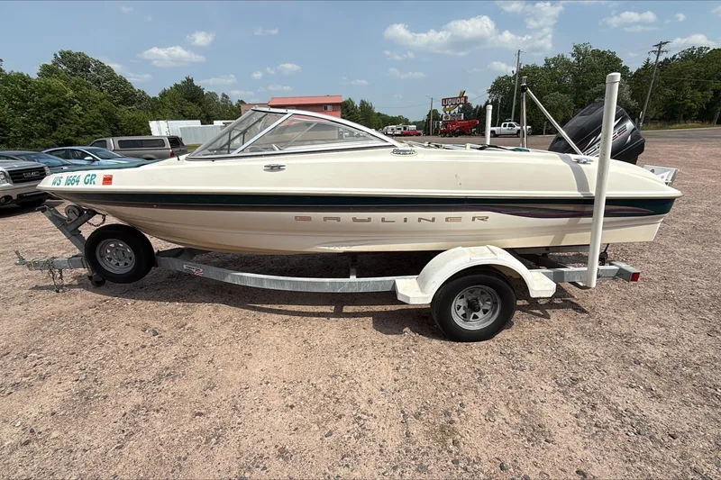 Slide: The Image of 1999 Bayliner 1800 Capri boat on trailer, parked outdoors under a clear sky. - 6
