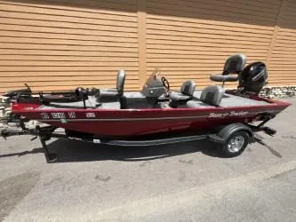 Slide: The Image of 2022 Tracker Bass Tracker Classic XL boat with red exterior, parked on a trailer. - 2