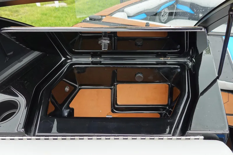Slide: The Image of Open storage compartment in 2023 Axis T250 boat, featuring sleek black and brown interior design. - 28