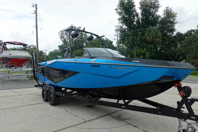Slide: The Image of 2023 Axis T250 boat in vibrant blue on a trailer, parked outdoors. - 4