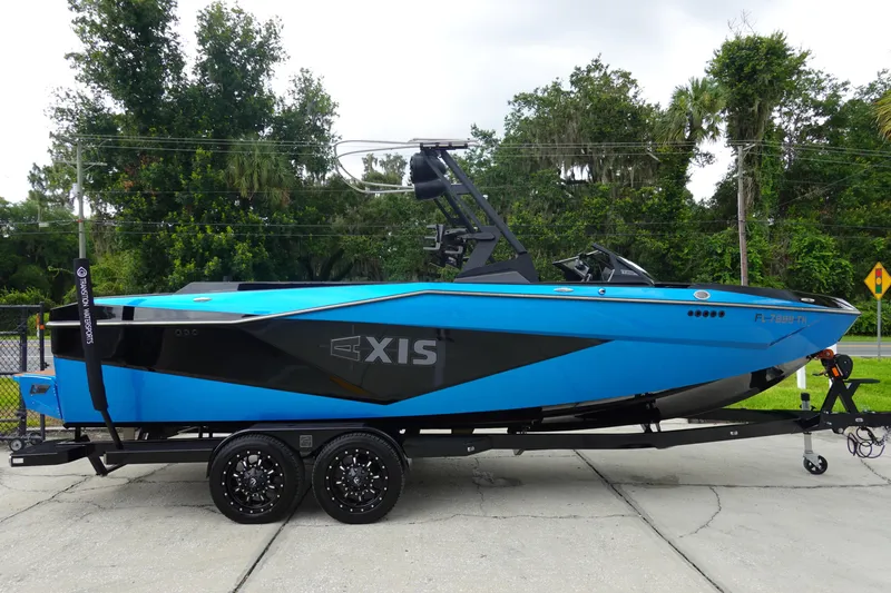 Slide: The Image of 2023 Axis T250 boat in vibrant blue on a trailer, parked outdoors. - 5