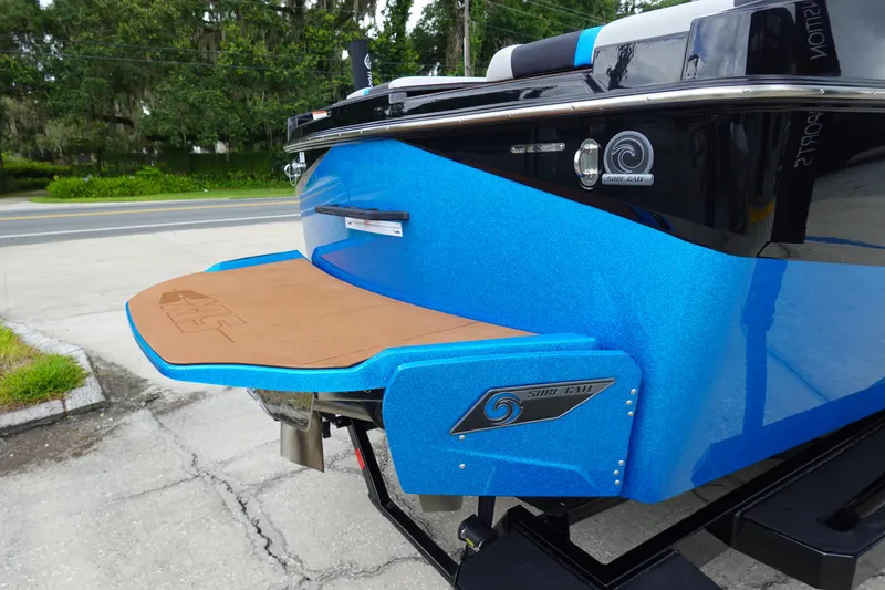 Slide: The Image of 2023 Axis T250 boat with blue hull and swim platform, parked on pavement. - 6