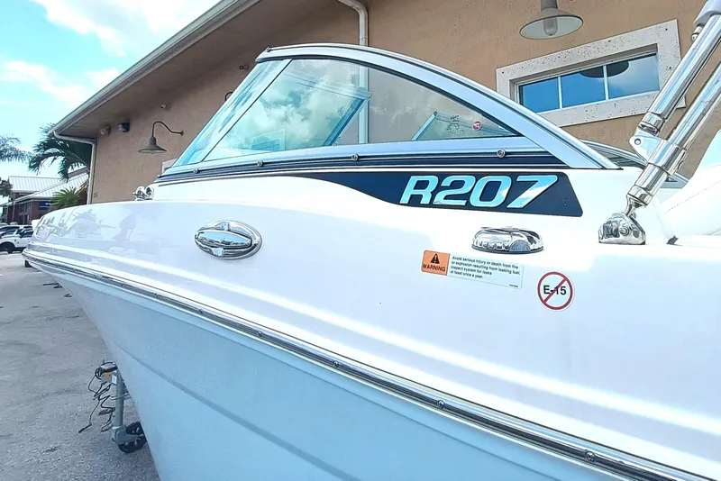 Slide: The Image of 2024 Robalo R207 Dual Console boat, white exterior, docked near a building. - 5