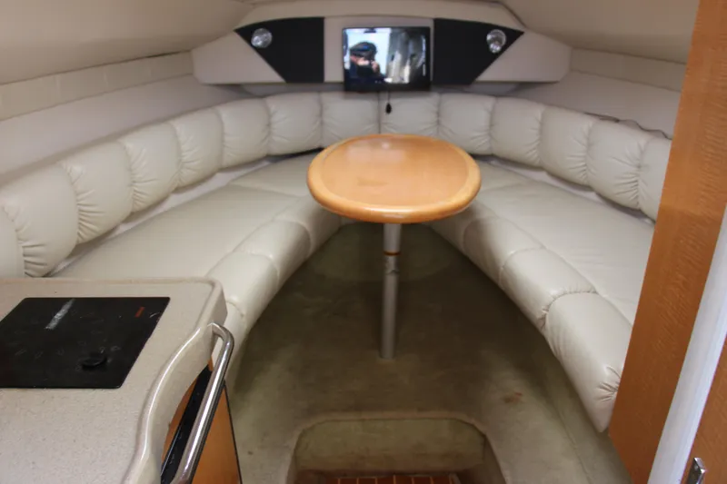 Slide: The Image of 2008 Larson Cabrio 260 cabin interior with cushioned seating and wooden table. - 15