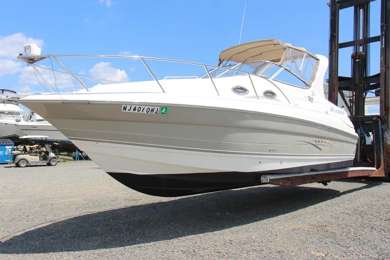 Slide: The Image of 2008 Larson Cabrio 260 boat on forklift, displayed outdoors under blue sky. - 2