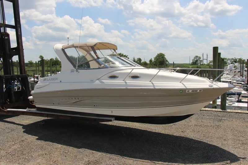 Slide: The Image of 2008 Larson Cabrio 260 boat lifted on a forklift, sunny day, marina background. - 5