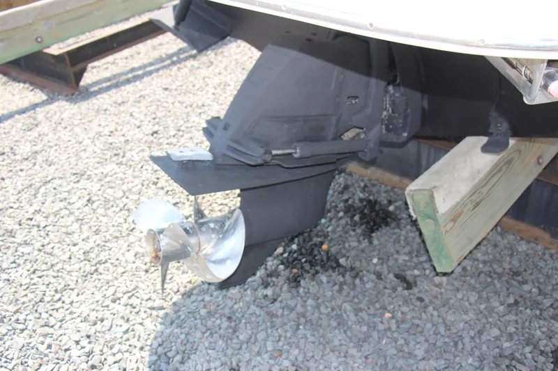 Slide: The Image of 2008 Larson Cabrio 260 boat propeller and stern drive on gravel surface. - 7
