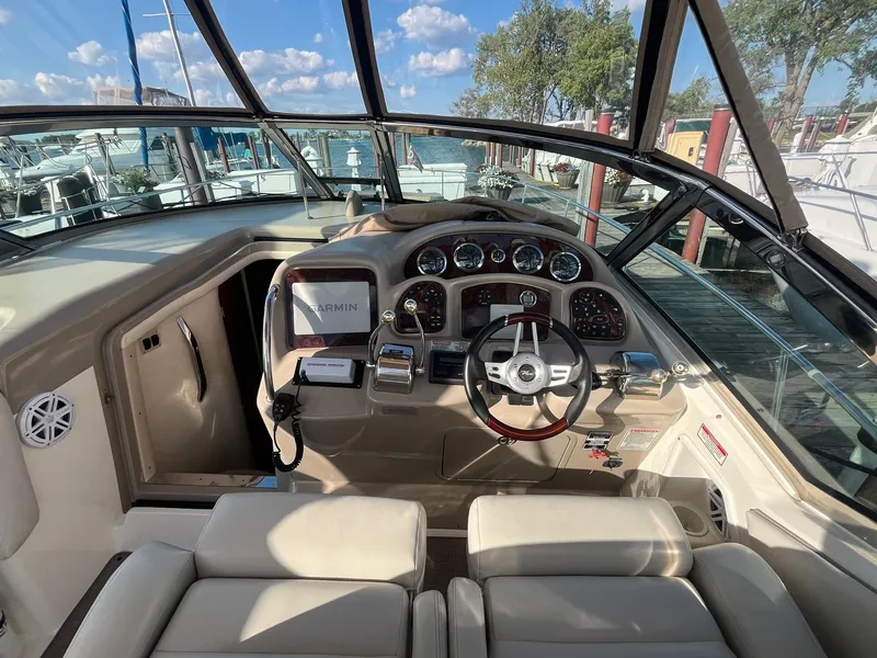 Slide: The Image of 2002 Sea Ray 320 Sundancer helm with Garmin navigation, docked by a scenic waterfront. - 12