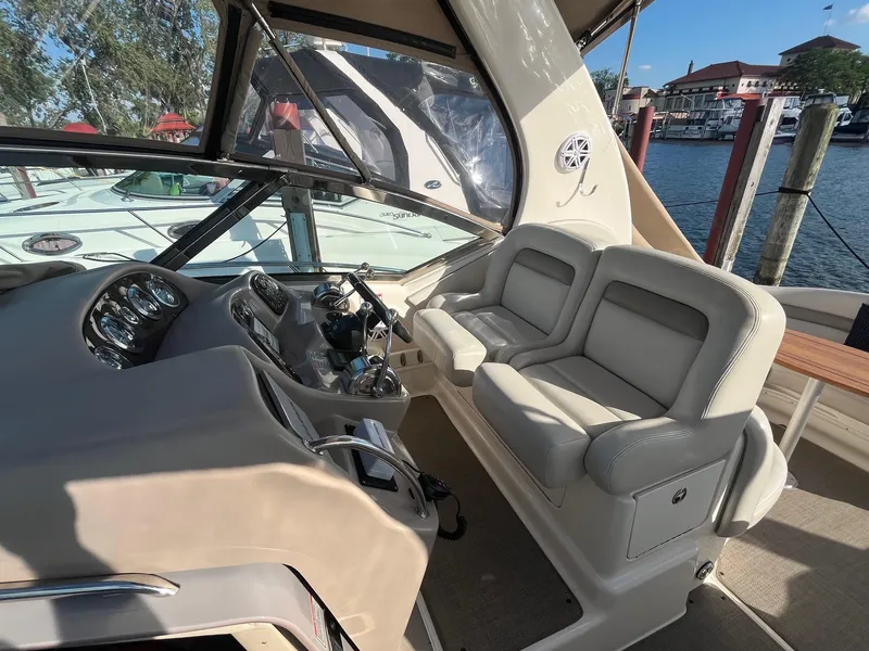 Slide: The Image of 2002 Sea Ray 320 Sundancer helm with dual seats and control panel, docked at marina. - 13