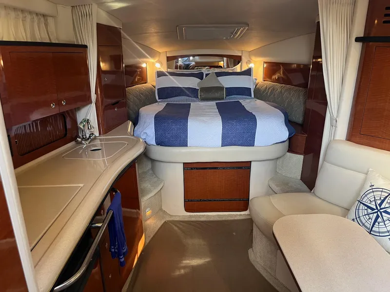 Slide: The Image of 2002 Sea Ray 320 Sundancer cabin interior with bed, kitchenette, and seating area. - 21