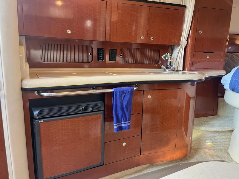 Slide: The Image of Interior of 2002 Sea Ray 320 Sundancer yacht with wooden cabinetry and compact kitchen area. - 25