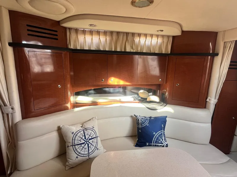 Slide: The Image of Interior of 2002 Sea Ray 320 Sundancer with cushioned seating and nautical-themed pillows. - 30