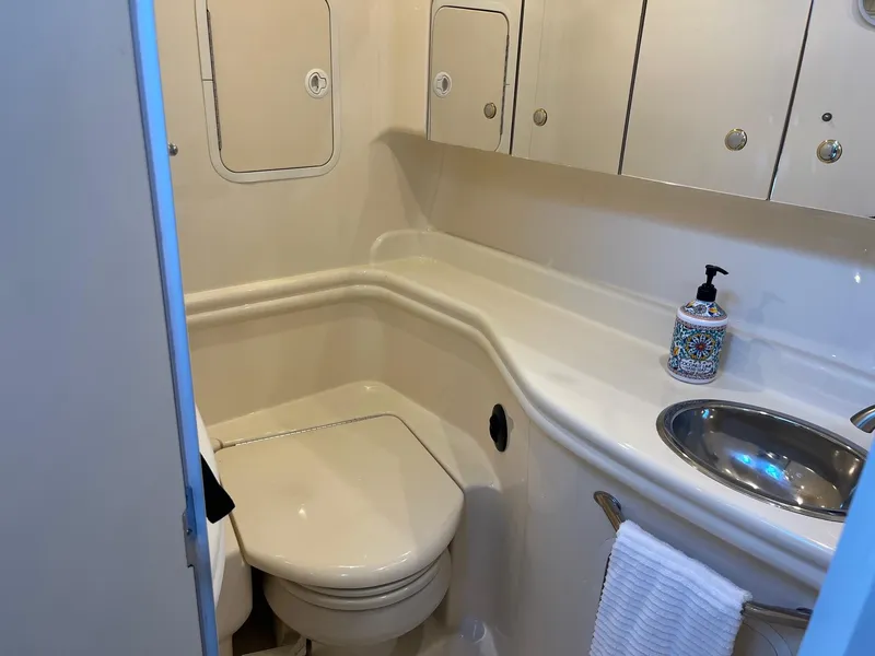 Slide: The Image of 2002 Sea Ray 320 Sundancer bathroom with toilet, sink, and storage cabinets. - 35