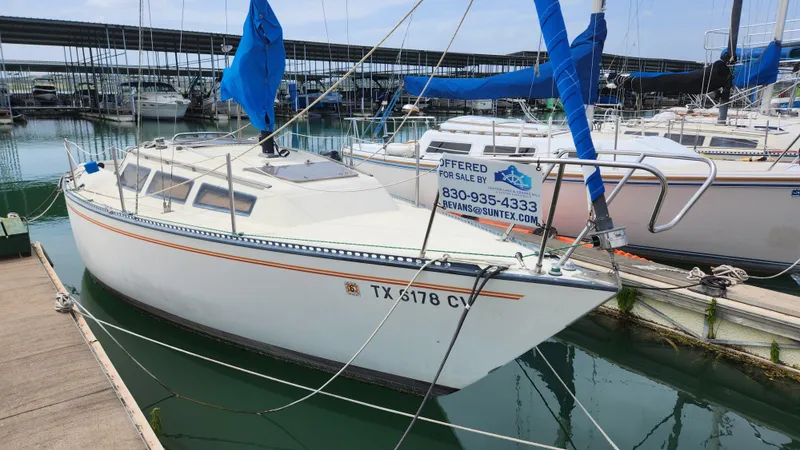 Slide: The Image of 1980 S2 7.3 sailboat docked at marina, blue sails, for sale sign visible. - 0