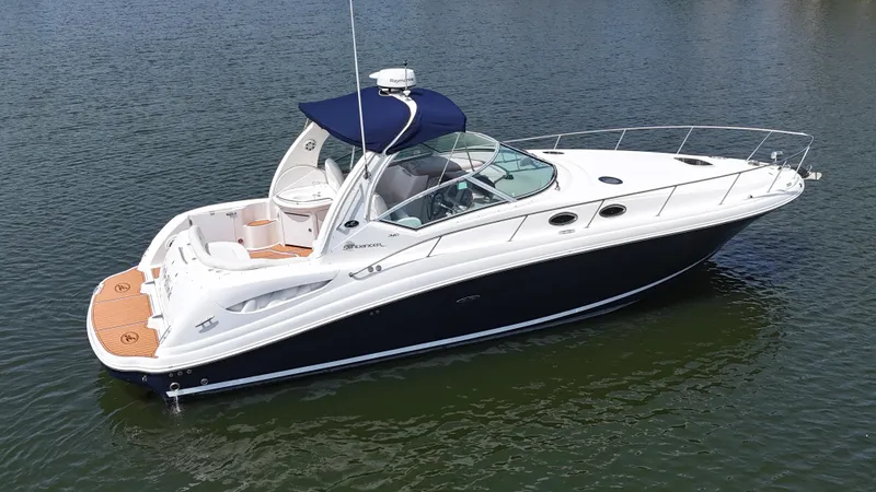 The Image of 2005 Sea Ray 340 Sundancer yacht on calm water, featuring sleek design and blue canopy. - 0