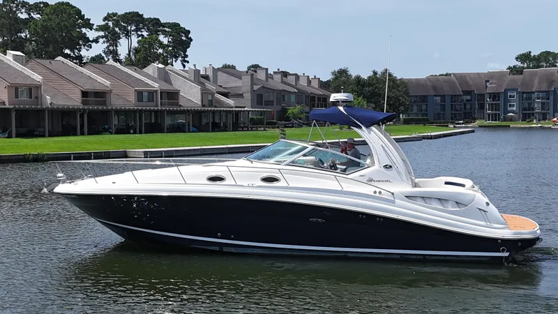 Slide: The Image of 2005 Sea Ray 340 Sundancer yacht cruising on a calm lake near residential buildings. - 25
