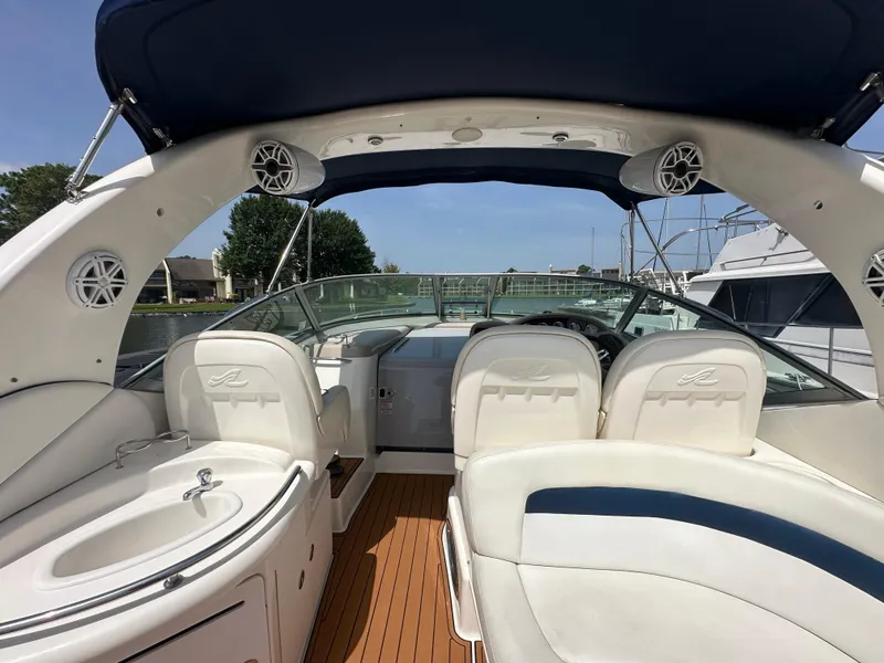 Slide: The Image of 2005 Sea Ray 340 Sundancer boat interior with seating and helm, docked under blue sky. - 36