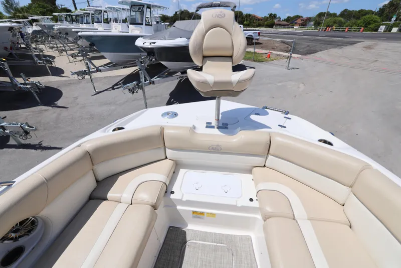 Slide: The Image of 2017 NauticStar 243DC Sport Deck boat with beige seating, docked in a marina. - 2