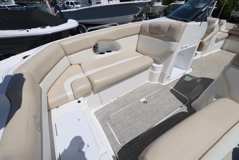 Slide: The Image of 2017 NauticStar 243DC Sport Deck interior with beige seating and open storage compartment. - 8