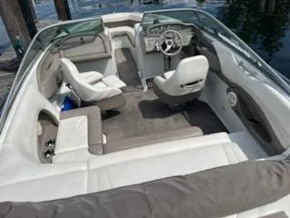 Slide: The Image of 1999 Cobalt 226 boat interior with white seating and steering wheel, docked by water. - 7