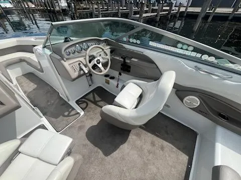 Slide: The Image of 1999 Cobalt 226 boat interior with steering wheel, dashboard, and seating, docked by the water. - 9