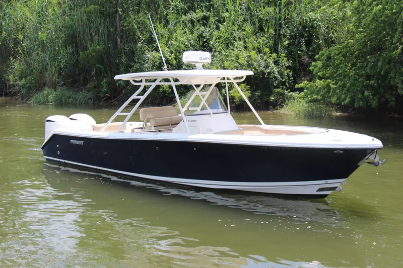 The Image of 2016 Pursuit S 280 Sport boat on calm water, surrounded by lush greenery. - 0