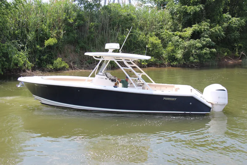 Slide: The Image of 2016 Pursuit S 280 Sport boat cruising on a calm river near lush greenery. - 8