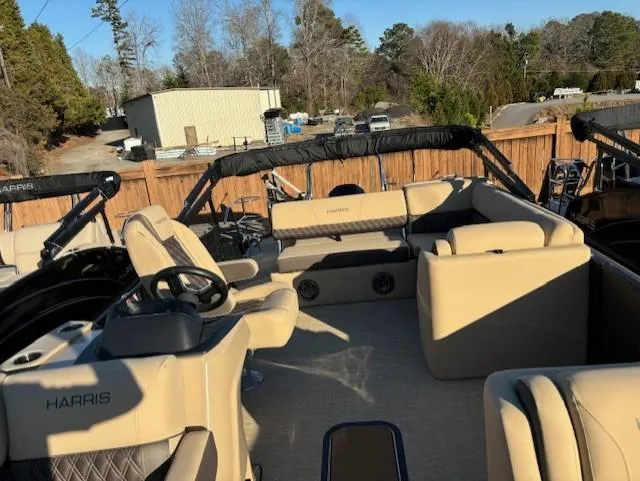 Slide: The Image of 2025 Harris Sunliner 230 pontoon boat with beige seating and steering wheel, docked outdoors. - 15