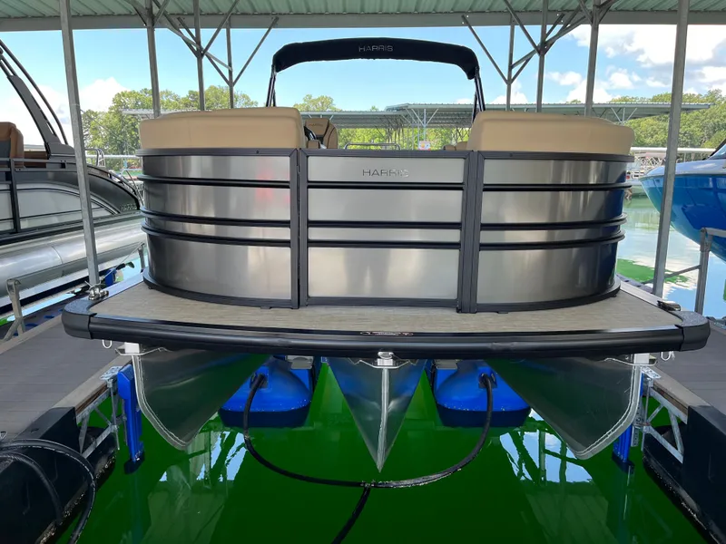 Slide: The Image of 2025 Harris Sunliner 230 pontoon boat docked under a covered marina. - 2