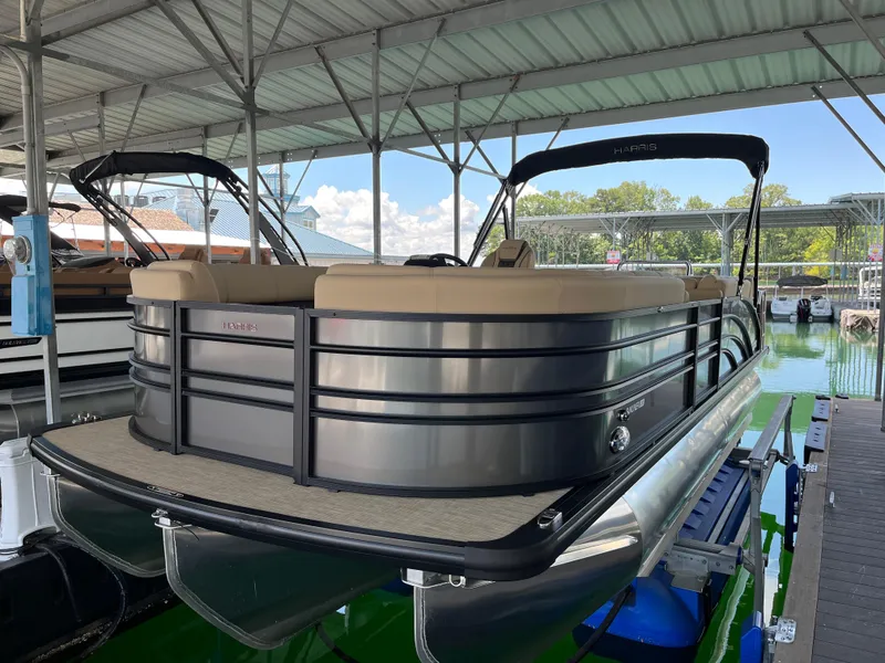 Slide: The Image of 2025 Harris Sunliner 230 pontoon boat docked under a covered marina. - 5