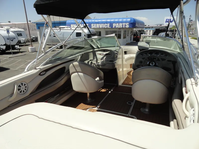 Slide: The Image of 2002 Sea Ray 220 Bow Rider interior with steering wheel and seating, parked near service center. - 13