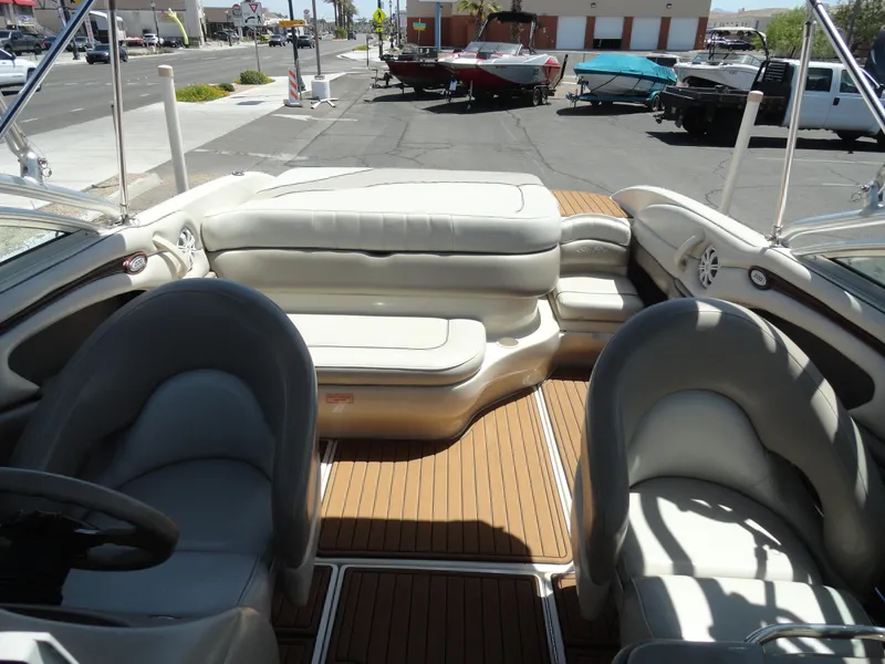 Slide: The Image of 2002 Sea Ray 220 Bow Rider interior with beige seating and wood flooring, parked outdoors. - 15