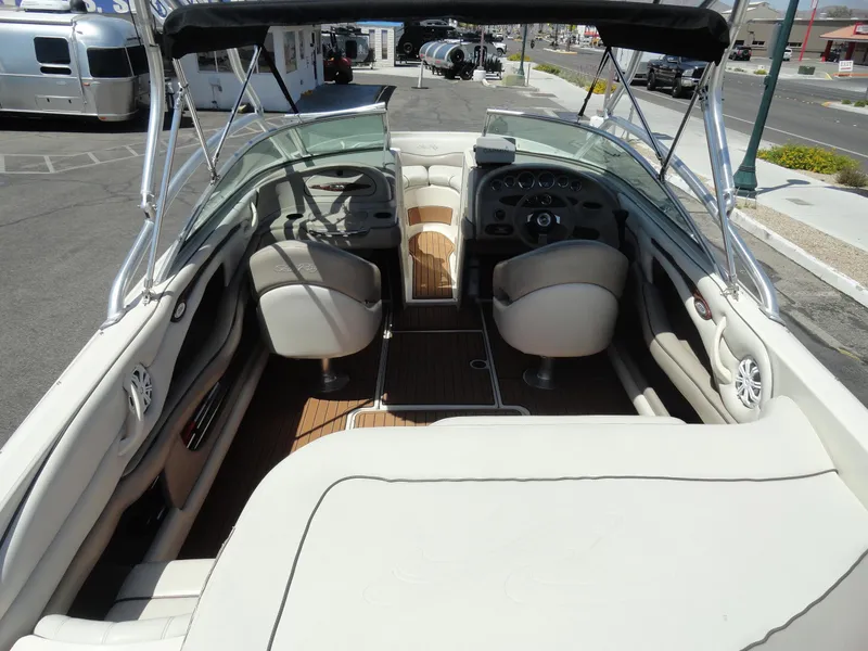 Slide: The Image of 2002 Sea Ray 220 Bow Rider interior with seating and steering wheel, parked outdoors. - 6