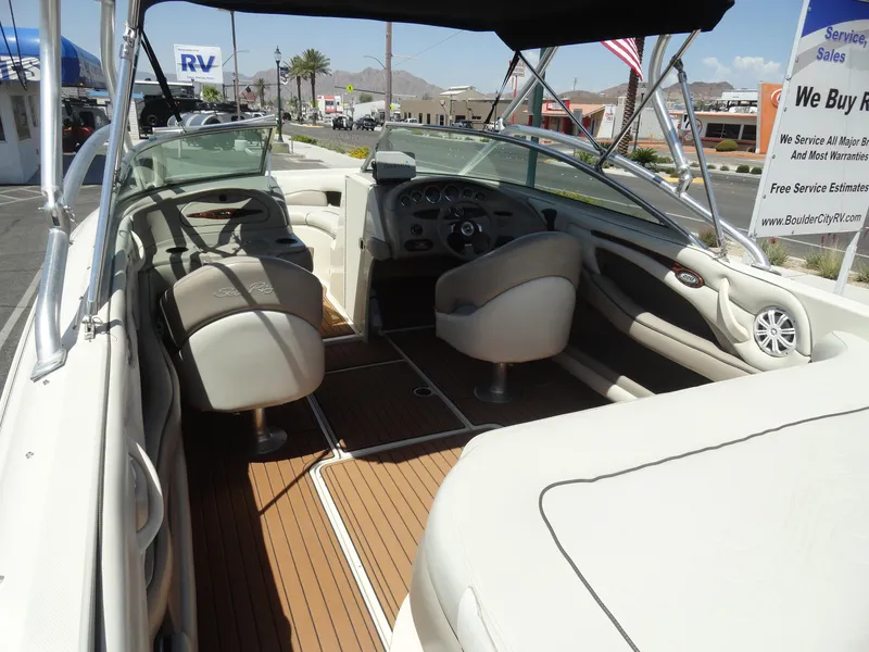 Slide: The Image of 2002 Sea Ray 220 Bow Rider interior with beige seating and wood flooring. - 7