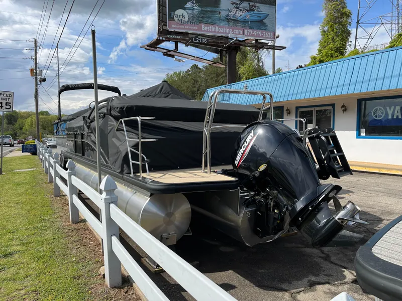 Slide: The Image of 2025 Harris Cruiser 230 pontoon boat with Mercury engine, parked near a marine center. - 2