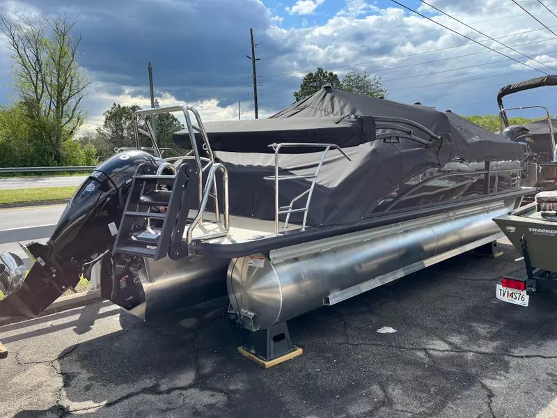 Slide: The Image of 2025 Harris Cruiser 230 pontoon boat with cover, parked outdoors under cloudy sky. - 3